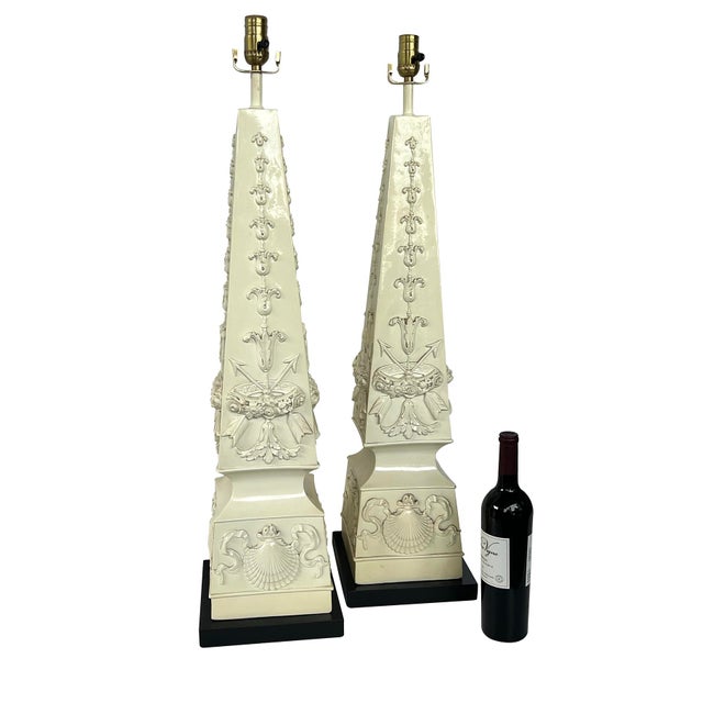 each classically inspired obelisk form lamp of imposing size all in a creamware glaze featuring classical relief motifs of...