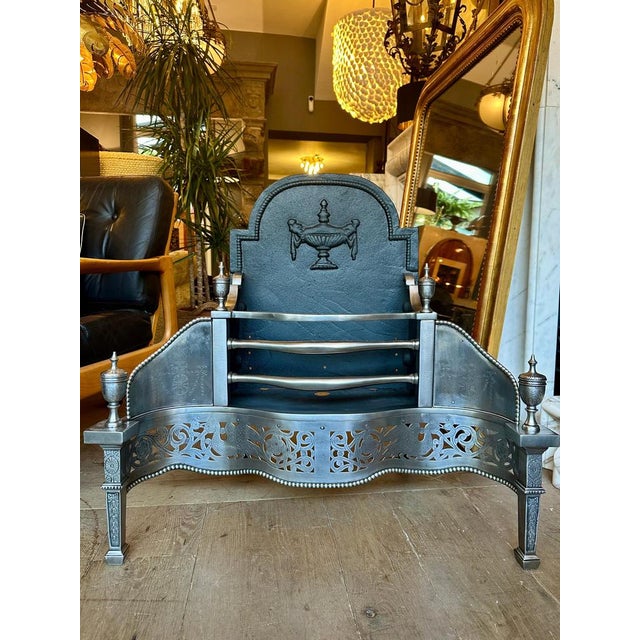 A Mid 19th century Georgian style Dog grate, in polished steel and wrought iron. The deeply engraved and cut fret of...