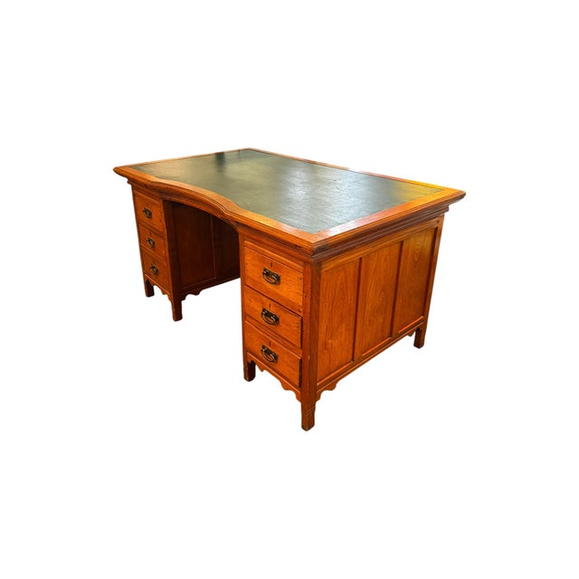 A timeless and substantial antique English partner’s desk, crafted in warm-toned wood with classic paneled detailing and a...