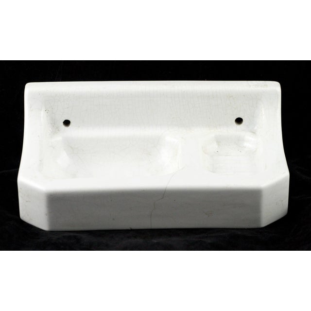 A European surface mount holder for soap and sponge, made from white porcelain with a subtle crackled glaze. This piece...