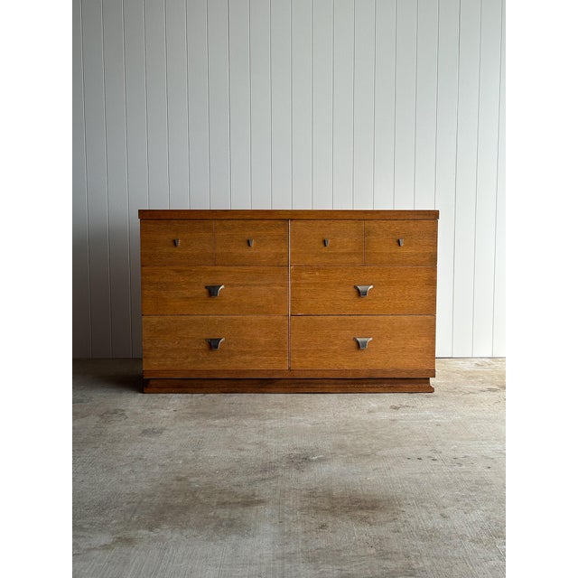 Vintage mid-century oak 6-drawer dresser with a rectilinear case and integrated plinth base. Original sculptural metal...