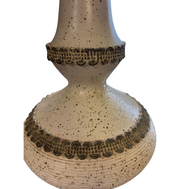 Vintage ceramic table lamp featuring a tall sculptural silhouette, speckled ivory glaze, incised ribbed texture, and...