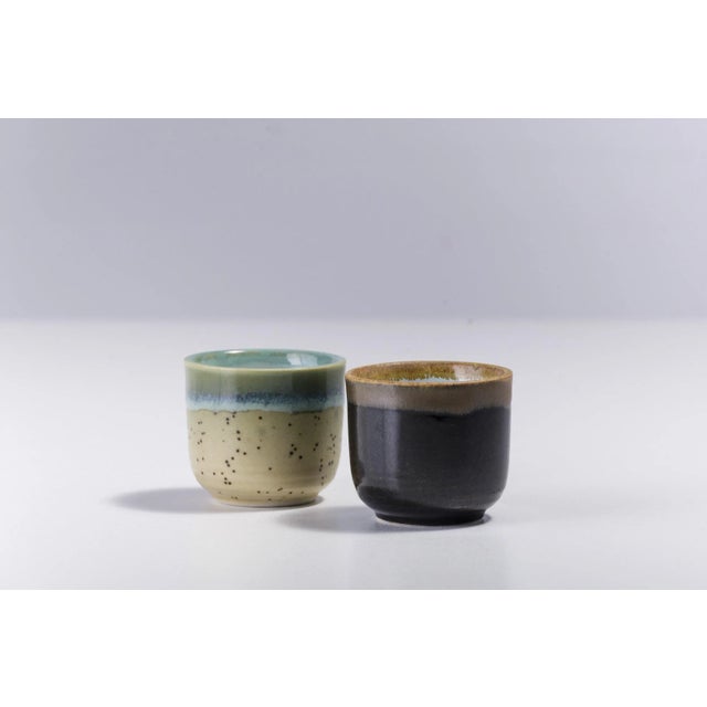 Incredible shades of rust and tobacco colors mark one of these two sake cups, combined with a second design distinguished...