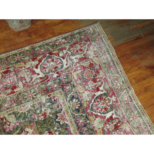 An early 20th century Persian Tabriz rug with a large herati design with raspberry and pink accent colors on a dark green...