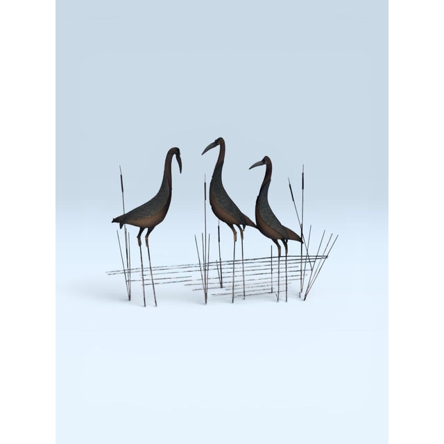 A striking and authentic signed Curtis Jeré metal sculpture depicting three elegant cranes standing amid stylized marsh...