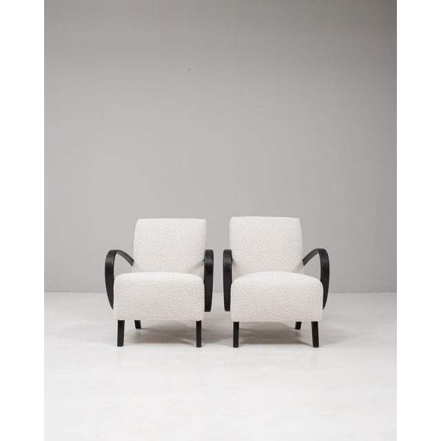 This pair of 20th Century Czech MCM upholstered armchairs by Jind?ich Halabala exemplifies the designers signature blend...