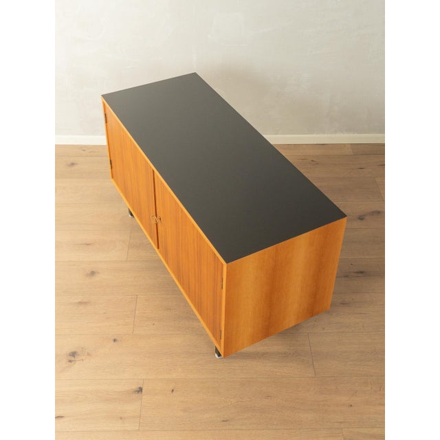 A wonderful sideboard from the 1960s. The body is finished in walnut veneer with two doors, one shelf, and new square...