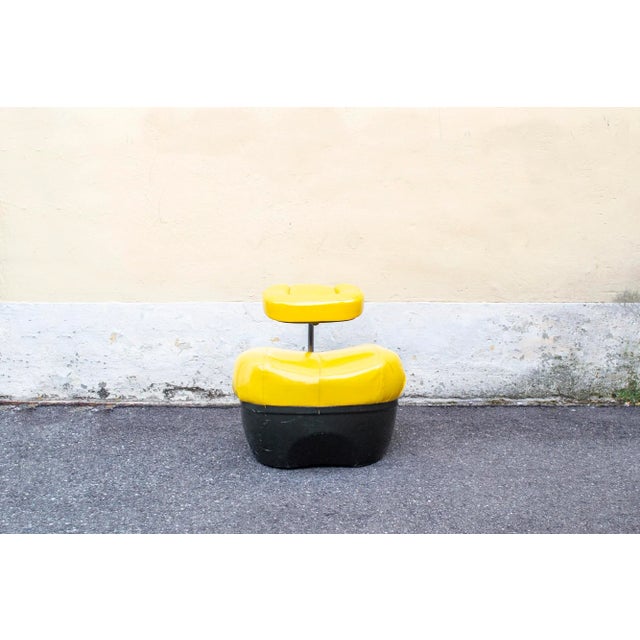Kneeling seat with black polystyrene base, stainless steel stem, flexible polyurethane padding and yellow leather coating...