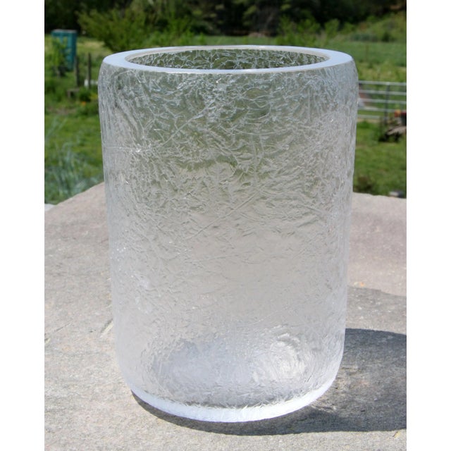 This heavy cylindrical vase is all about the glass itself, with an all-over crackle texture that catches light across the...