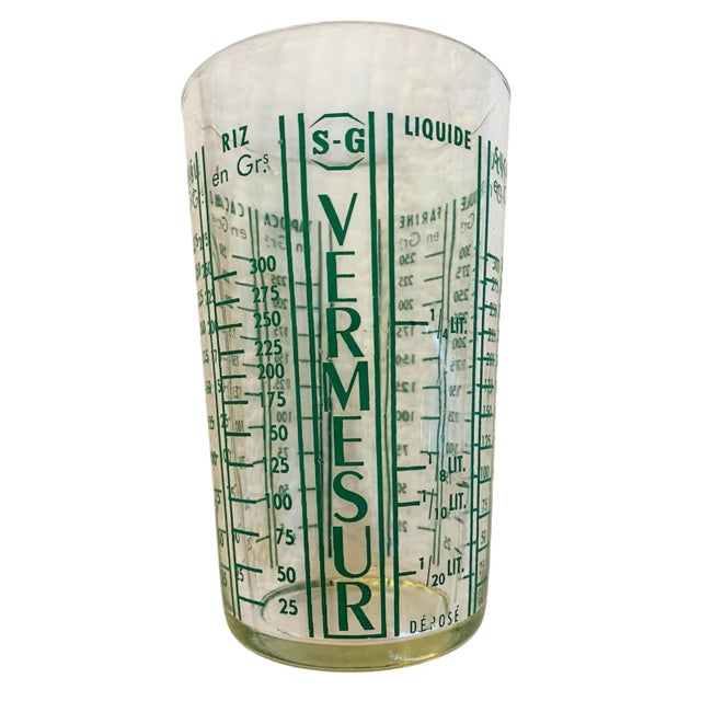 A vintage glass French measuring cup/tumbler with green print on clear glass. Dimensions are 3" diameter by 5.5" tall....