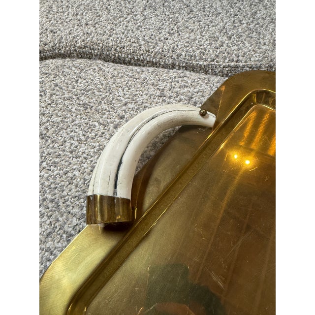 A distinctive Italian Mid-Century Modern serving tray crafted in polished brass, featuring elegant faux tusk handles with...