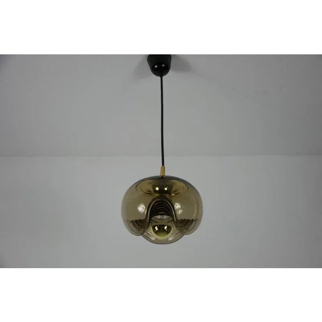 This pendant lamp by koch & lowy for peill and putzler, made in germany in the 1960s, captivates with its beautiful glass....