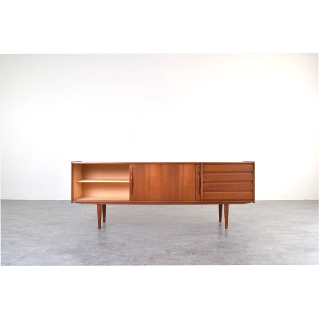 This teak sideboard was manufactured in Denmark in the 1960s. The piece of furniture has four drawers and a sliding,...