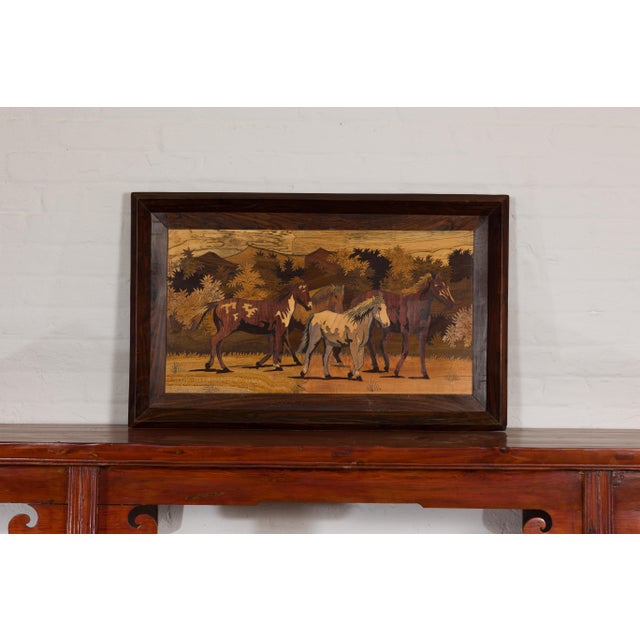 A vintage framed inlaid wood painting depicting four horses in a landscape in simple wooden frame. Experience the timeless...
