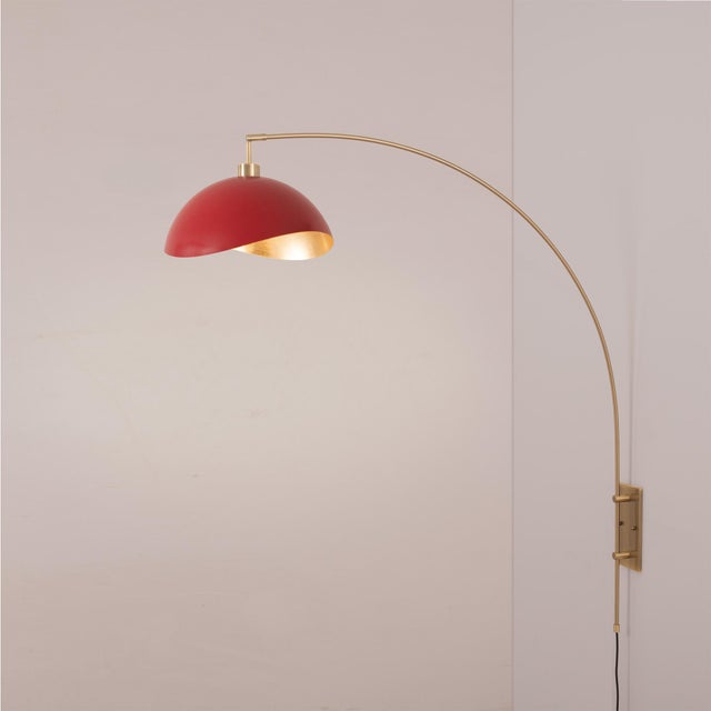 The Luna Bella Wall Arc Lamp is a striking arc lamp featuring a weathered brass steel body and a unique half-dome red/gold...