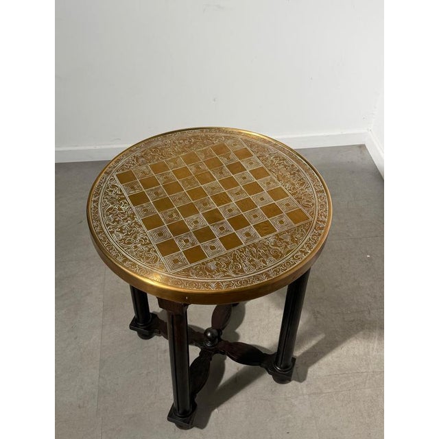 Characterful round side table featuring a copper top decorated with a chessboard pattern and intricate scrolling motifs....