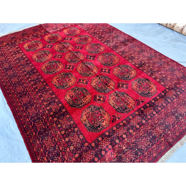 This vivid Turkmen Bokhara rug features a dense grid of octagonal "elephant's foot" guls in bright orange-rust and navy,...