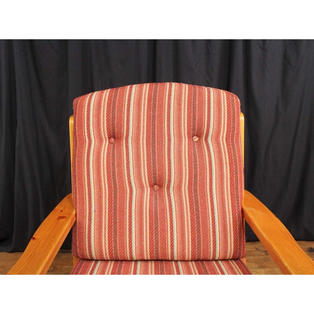 A vintage, Scandinavian style lounge armchair. The chair features a pine wood frame & removable striped cushions for the...