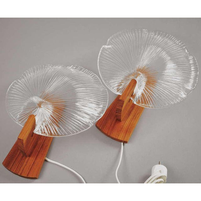 A pair of sconces by Eva Englund. Glass and teak. Measure: H 12.5" Existing European wiring, rewiring available.