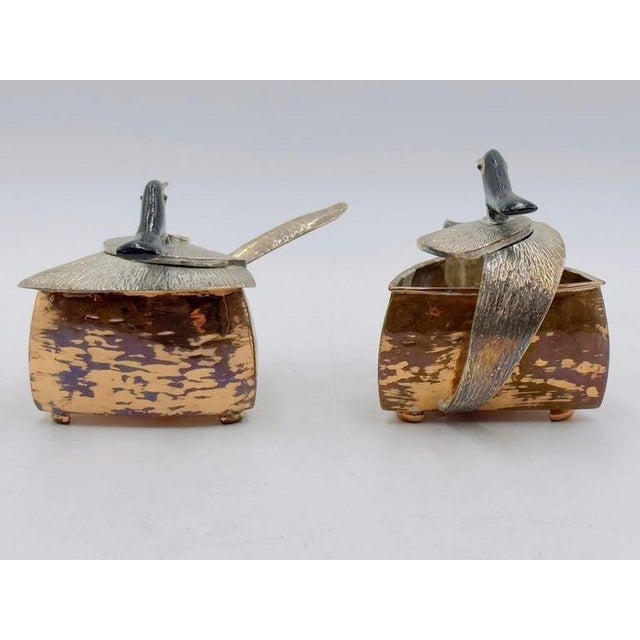 A whimsical and collectible three-piece copper and silver-plated creamer and sugar bowl set with matching spoon, designed...