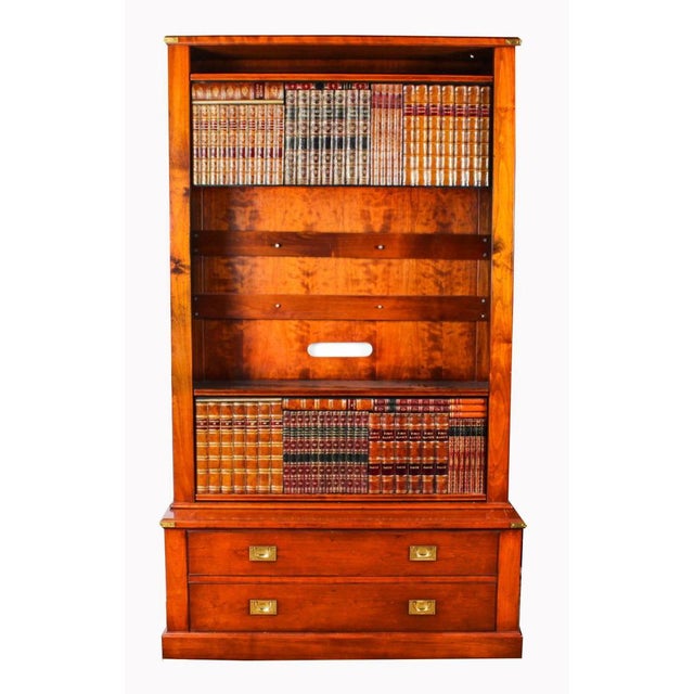 This is an elegant vintage english campaign style mahogany tv cabinet with faux book spine sliding doors, late 20th...