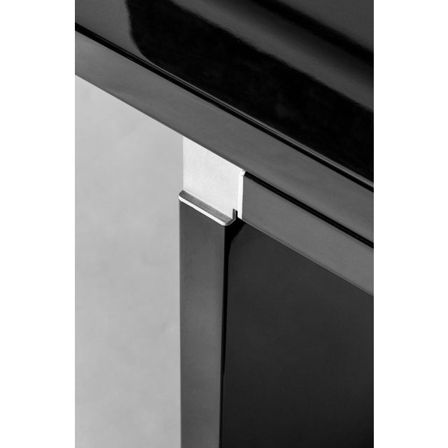 The table features a rectangular top with slightly rounded corners, crafted from black lacquered wood. The frame is...