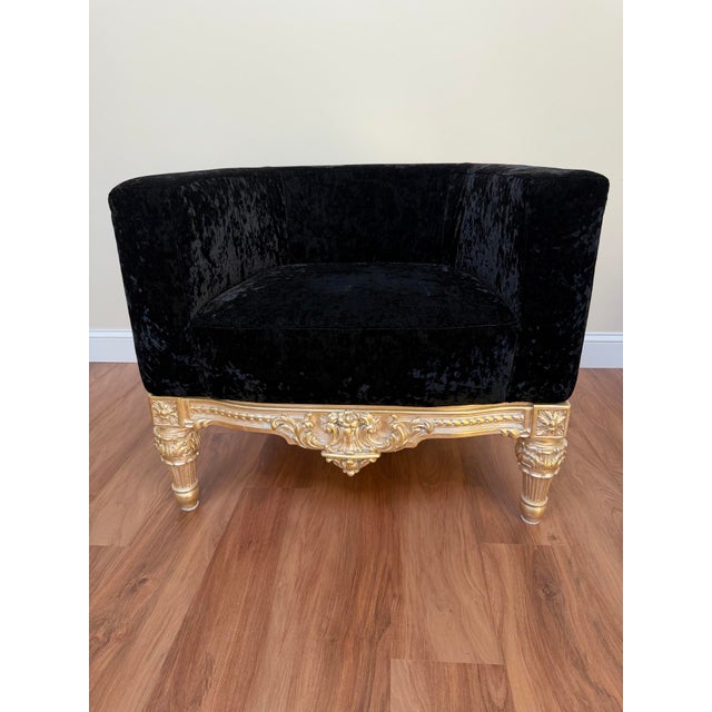 Custom upholstered tub chair in black crushed velvet with an ornate gilt-finished carved wood base, in a Hollywood Regency...