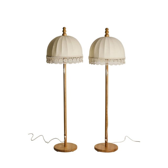 A pair of pine floor lamps with fabric and lace lampshades. The lampshades were designed by Yngve Ekström in the 70s. The...