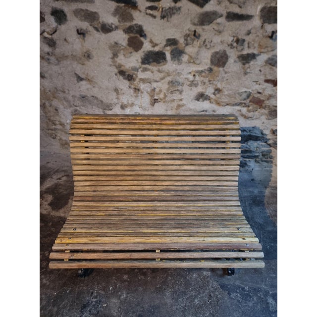 This French garden bench dates from the mid-20th century and is constructed from solid iron and wooden slats. The frame is...