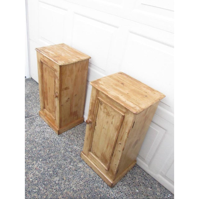 Pair of antique English rustic pine nightstands, c.1900 Having a rectangular top below which is a cupboard door, which...