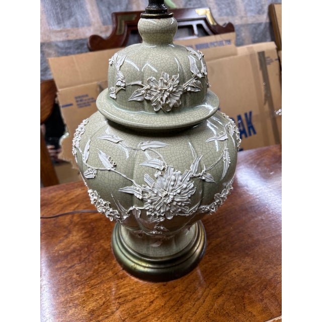 A beautifully detailed Chinoiserie-style ceramic table lamp featuring a soft celadon-green crackle glaze and sculptural...