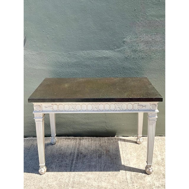 Exuding refined elegance, this vintage Neoclassical console table contrasts a dark polished stone top with a delicately...