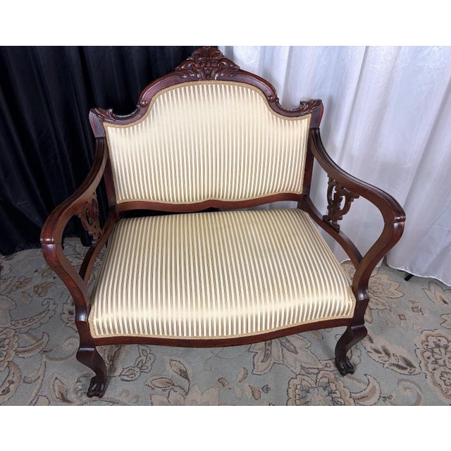 A captivating testament to old-world romance, this petite Victorian-era mahogany settee pairs dramatic grandeur with a...