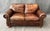 This Thomasville brown leather loveseat features a classic two-seat design with plush cushions, rolled arms, and nailhead...