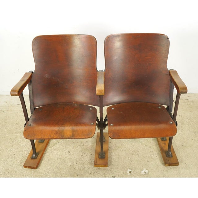 Vintage theater seats made of a dark stained wood seat and backrest with cast iron frames. The unit is screwed to three...