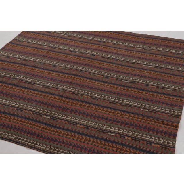 Handwoven in wool and originating circa 1950-1960, this 6x6 vintage Persia kilim and square rug is a rich tribal curation...