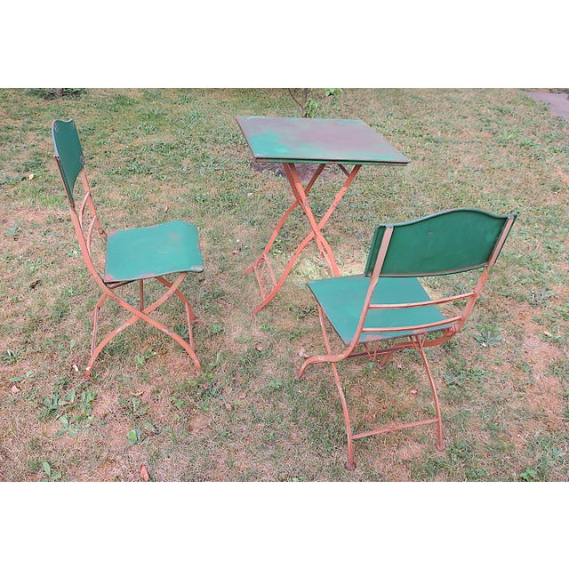 Mid century forest green and salmon painted iron garden table and 2 matching chairs full of character, well patinated. The...