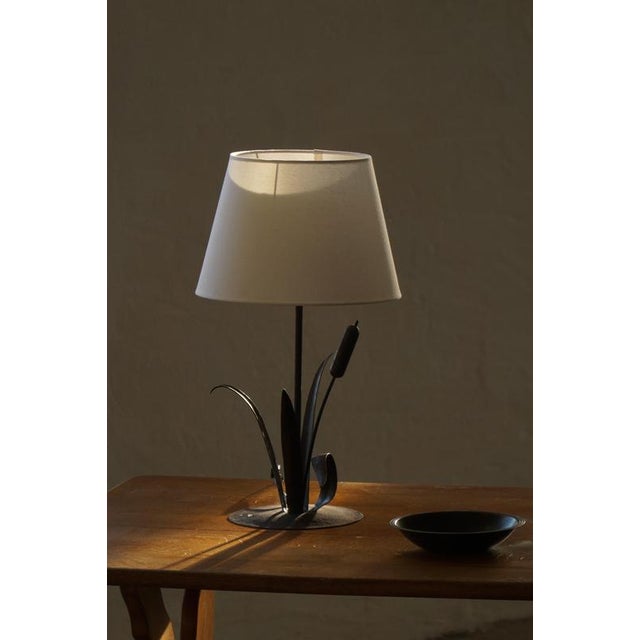 A beautiful and unique sculptural table lamp crafted in wrought iron, dating to the mid-20th century. The lamp features an...