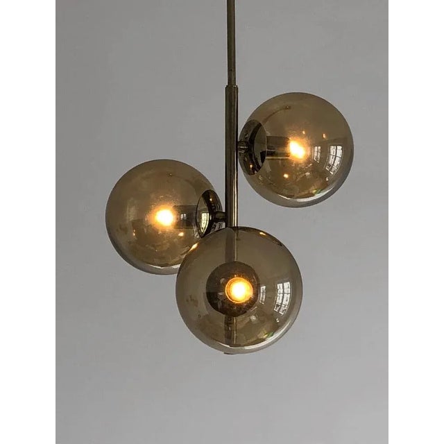 An elegant and rigorous 3-light pendant light, post-modernist, seventies, space-age, tubular structure in "smoked chrome",...