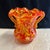 Small blown glass vase in swirls of orange, red and yellow. The vase has fused class handles.
