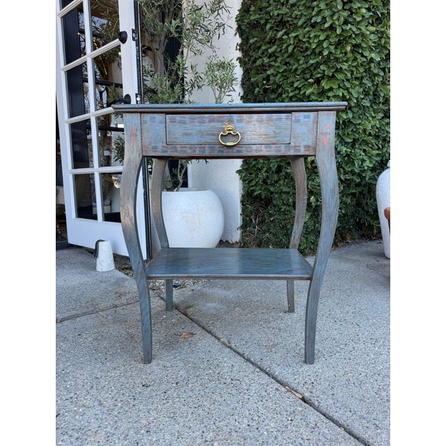 Charming vintage-inspired accent table featuring a distressed slate blue finish with subtle teal undertones and hints of...