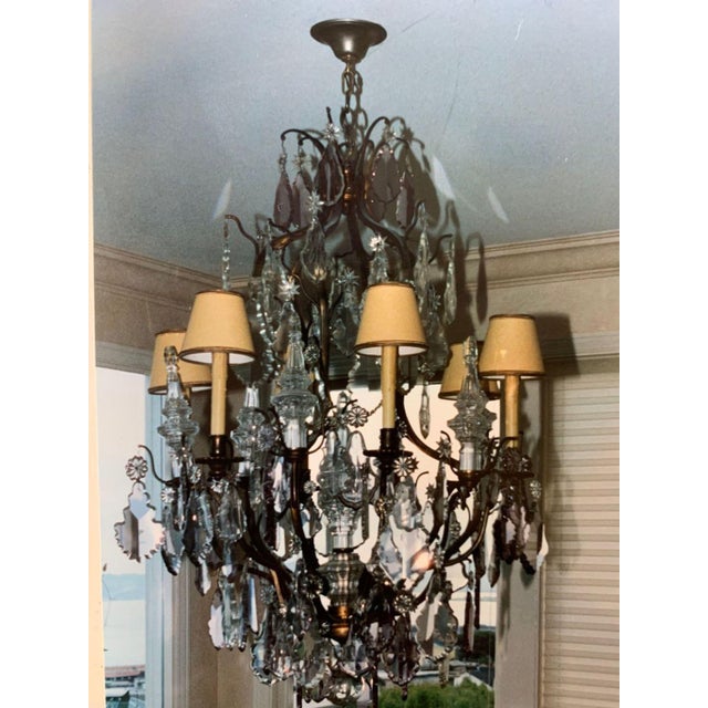 Grand Louis XV-style multi-light chandelier featuring an ornate scrolling metal frame lavishly adorned with faceted...