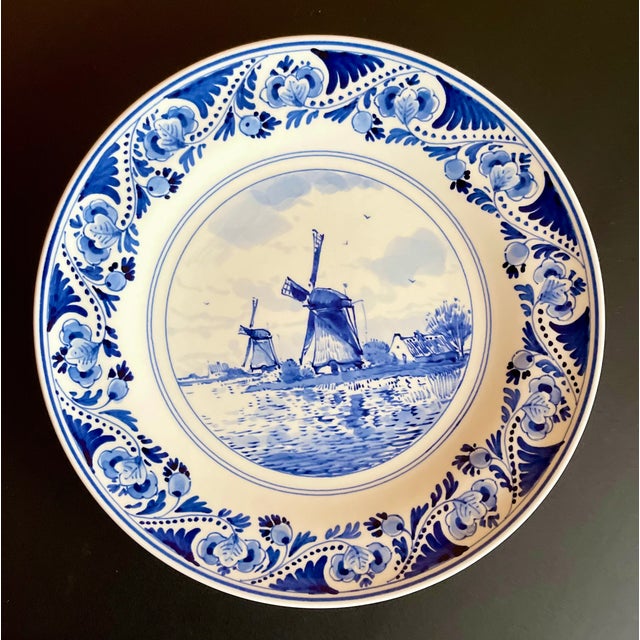 Royal Delft hand painted plate with a traditional windmill scene surrounded by a foliate design. Produced in the late 20th...