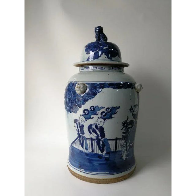 This blue and white porcelain jar is adorned with hand painted children happily playing outside on one side and simple...