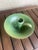 This item is a green glazed ceramic candle holder, specifically a style known as a chamberstick. It features a distinctive...