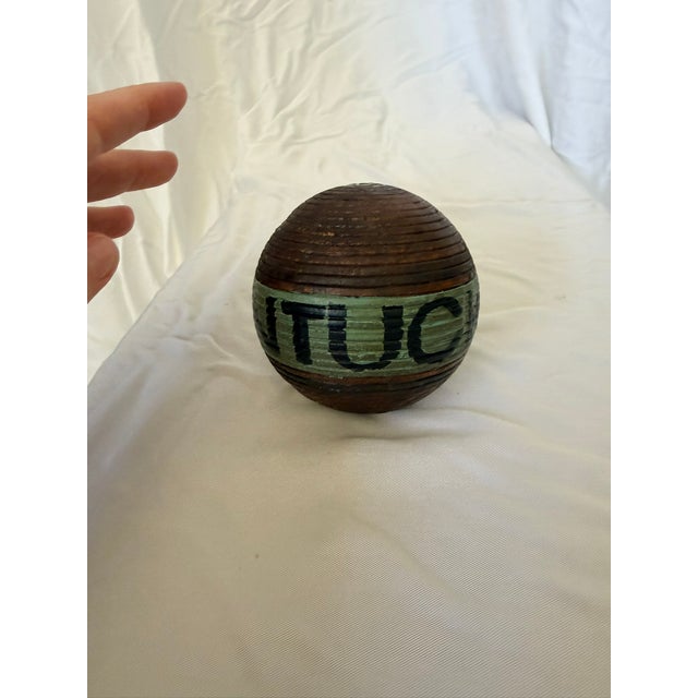 Vintage turned-wood lawn bowling ball featuring concentric carved rings and a hand-painted green band lettered...