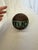 Vintage turned-wood lawn bowling ball featuring concentric carved rings and a hand-painted green band lettered...