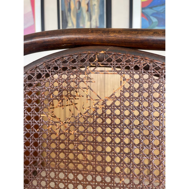 An elegant bentwood settee featuring three distinct cane-backed panels and scrolled armrests. Has a small tear on the left...