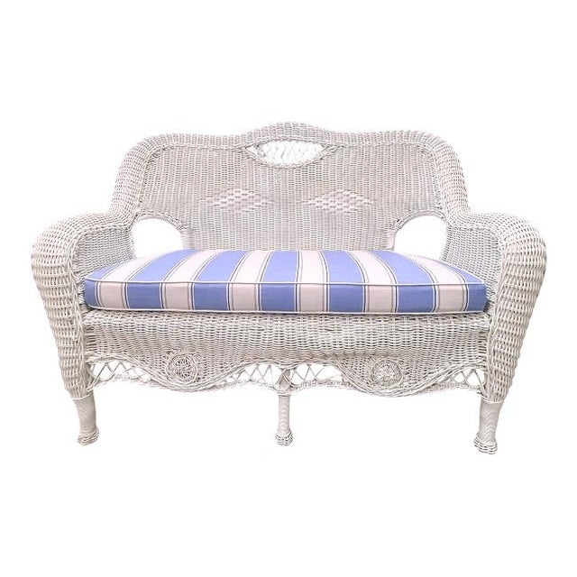 Vintage white wicker settee featuring beautifully detailed handwoven craftsmanship and an elegant scalloped silhouette....