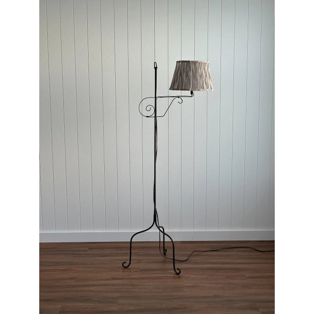 This vintage wrought iron floor lamp dates to the 1940s and features an adjustable swing arm with sculptural scroll...